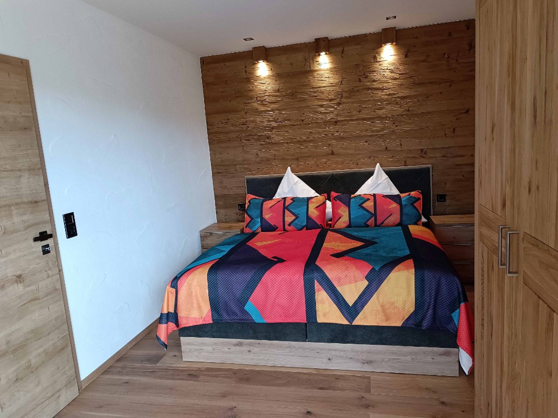 Ferienwohnung Chalet Seenähe - Schlafzimmer 1 mit Boxspringbett und TV
